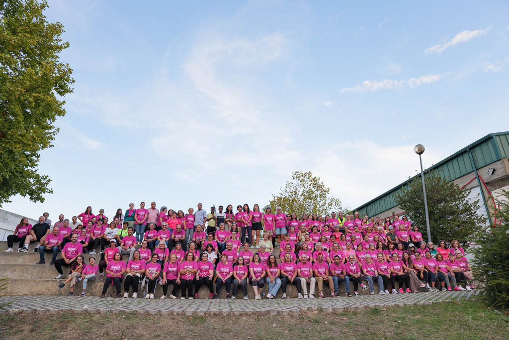 Participantes da caminhada, de t-shirt cor-de-rosa, reunidos nas bancadas exteriores.