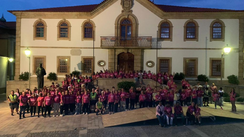 Grupo de caminhantes reunido em frente à Câmara Municipal, ao anoitecer.
