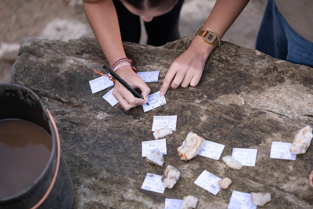 Aluna a escrever etiquetas para identificar os achados arqueológicos.